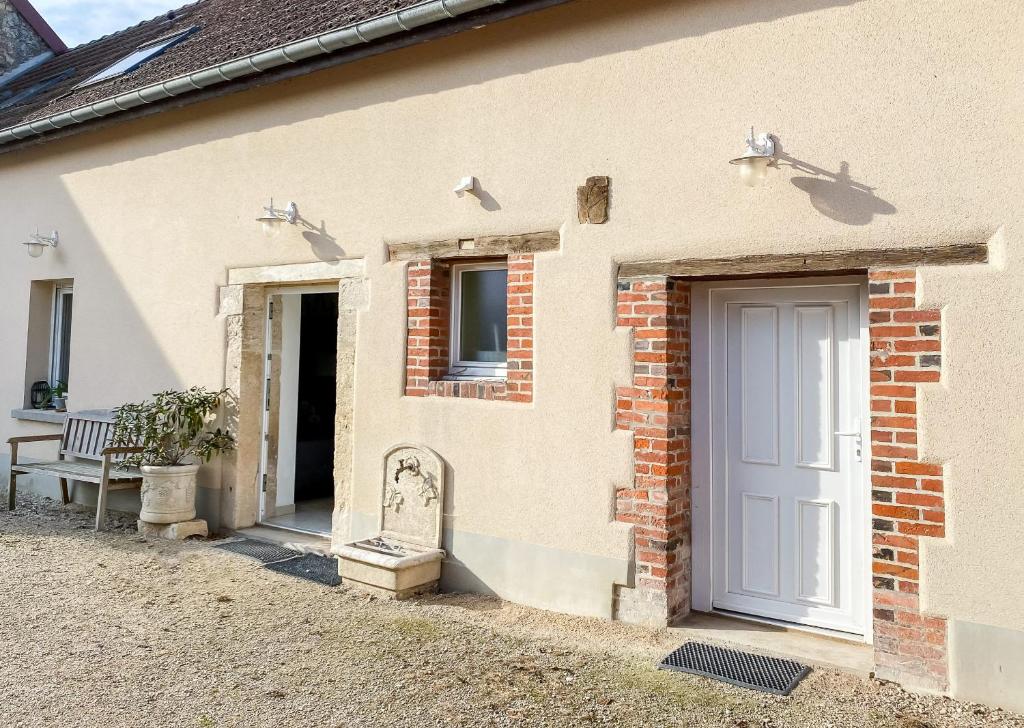 a white house with a door and a bench at La Grange de Flavigny in Flavigny