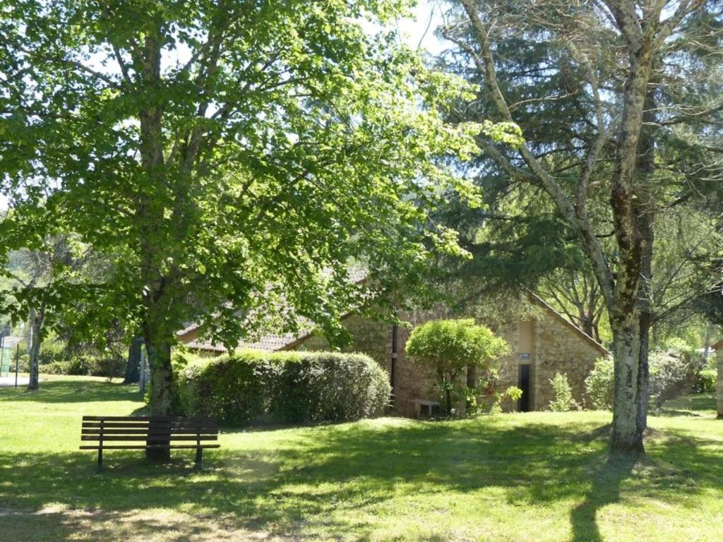 a park bench sitting under two trees in a park at ZEcamping 3 étoiles animaux acceptés piscine et Canoë Kayak in Chambonas