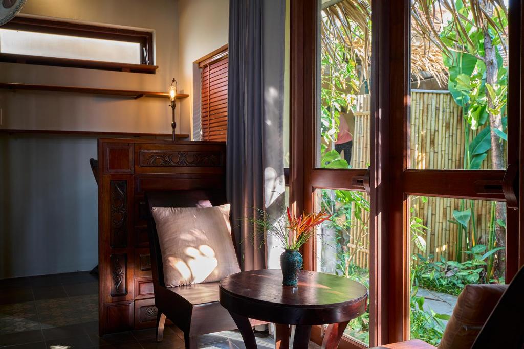 a room with a table and a chair and a window at Anicca Riverside Cottage in Thanh Ðông (1)