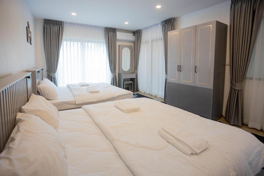 two beds in a hotel room with white sheets at Vera Cozy Stay 2 in Ban Zong Katiam