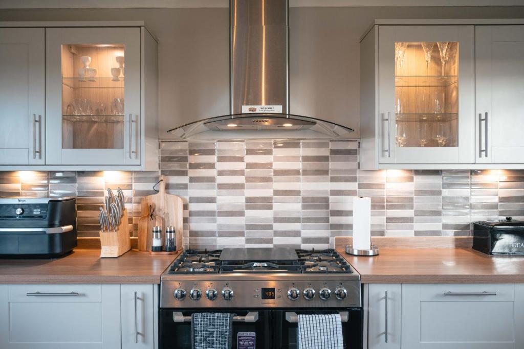 a kitchen with a stove and a tile back splash at Wildeston in Thurso