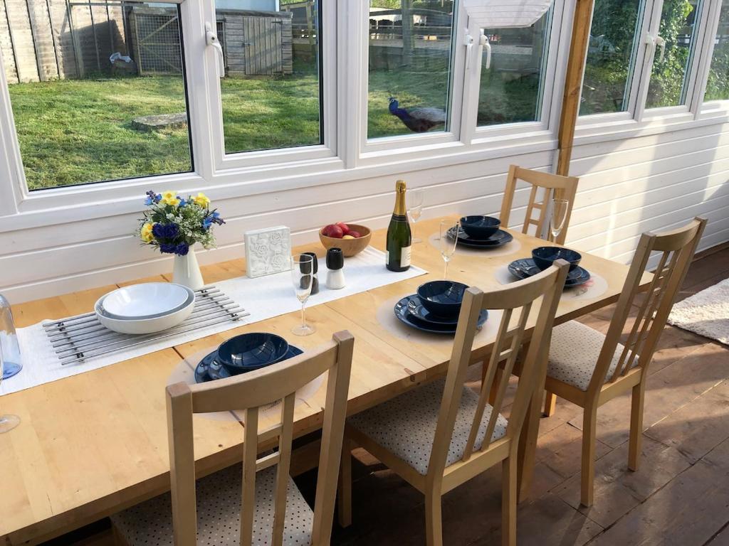 a wooden table with chairs and a bottle of wine at Stable Lodge in Williton