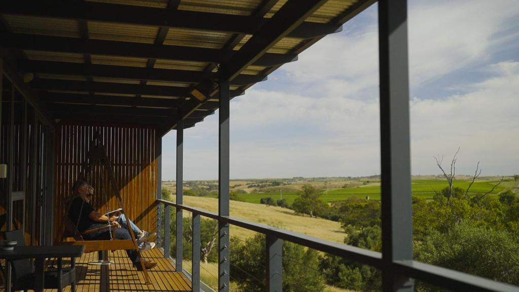 a woman sitting on a porch with a dog at Barossa Pavilions & Glasshouse in Lyndoch