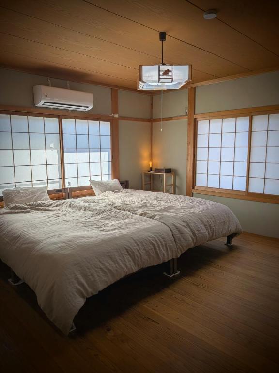 a bedroom with a large bed in a room with windows at とまり木 in Yoshino