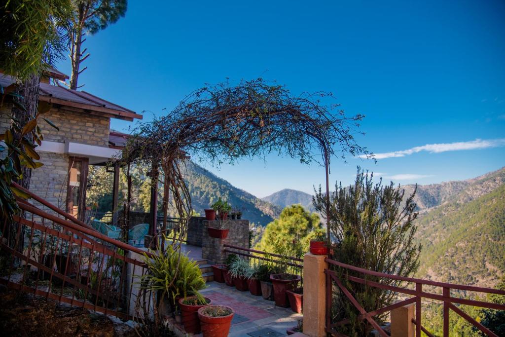 a house with a balcony with mountains in the background at Natural Elements by Levitate - Premium Two Room Chalet with Private Terrace Panoramic Forest View & Dedicated Kitchen in Rāmgarh