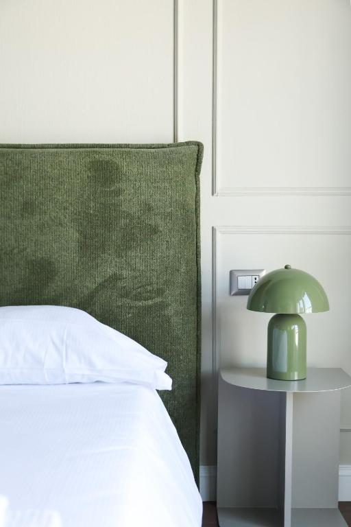 a green lamp on a table next to a bed at Corso Italia Rooms in Milan