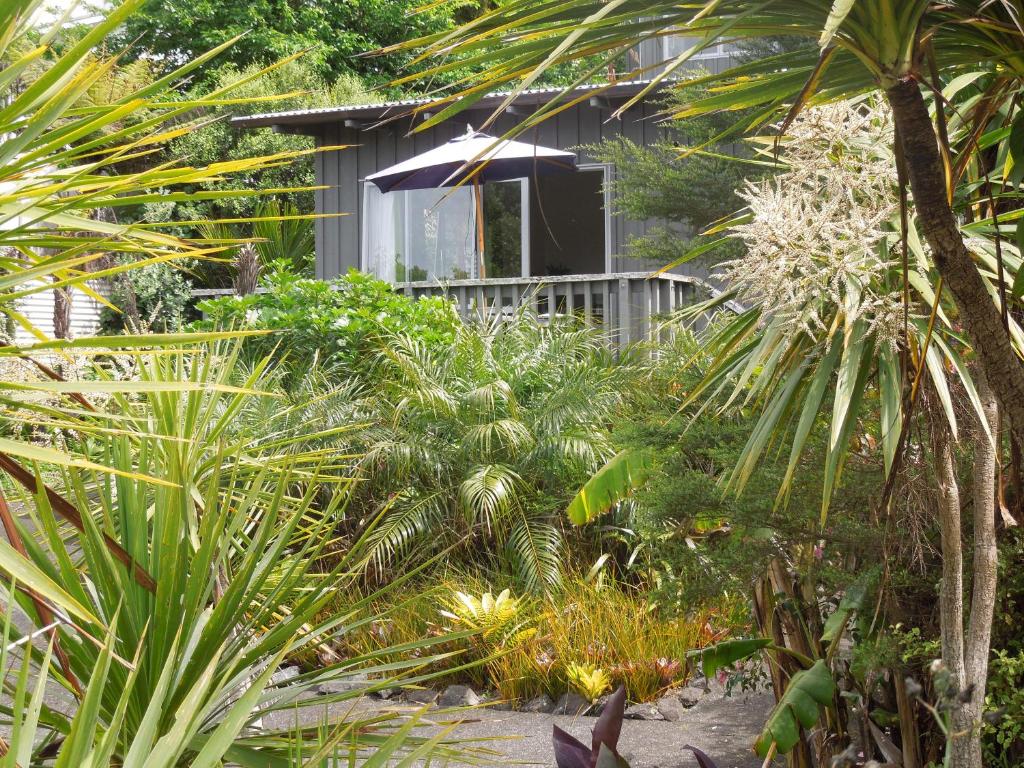 a garden with palm trees and a house at Island Breeze in Oneroa