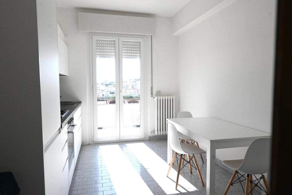 a white kitchen with a table and chairs and a window at S357 - Sirolo, luminoso trilocale con posto auto in Sirolo