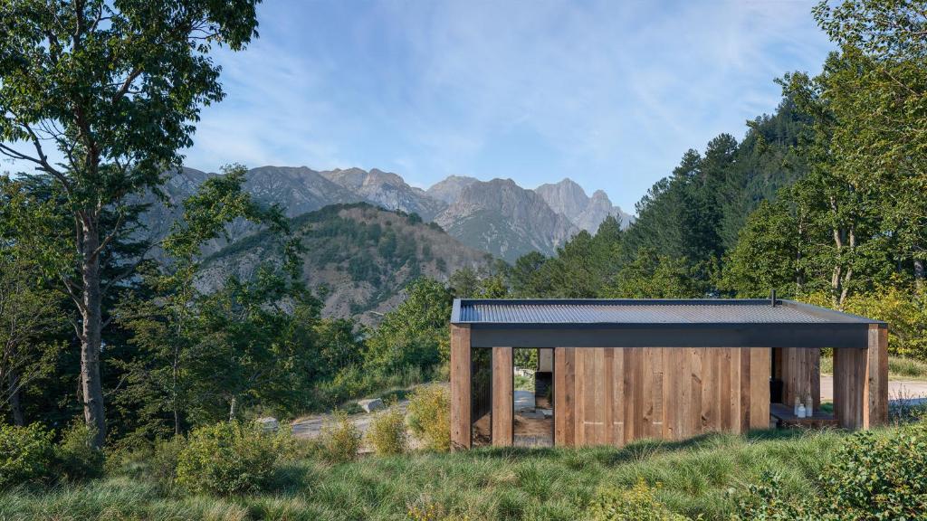 a wooden building in a field with mountains in the background at L'Acciola in Evisa