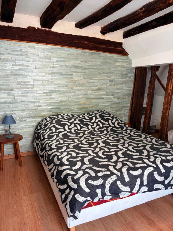 a bedroom with a bed with a black and white blanket at La Baraque de Beauval in Saint-Aignan