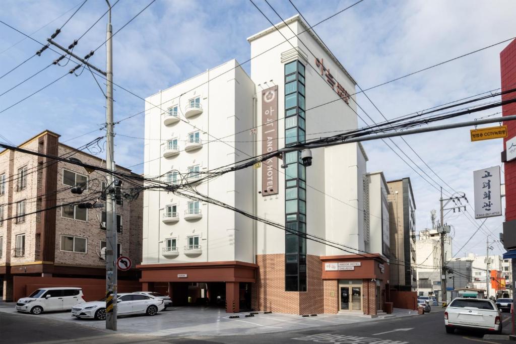 a tall white building with cars parked in front of it at Anook Hotel Jungangro Station in Daejeon