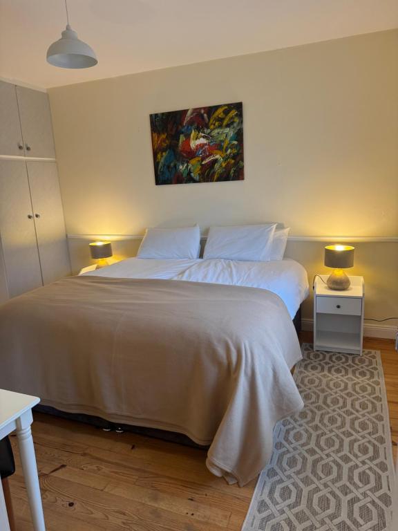 a bedroom with a large white bed with two lamps at Waterfront Apartment in Dingle
