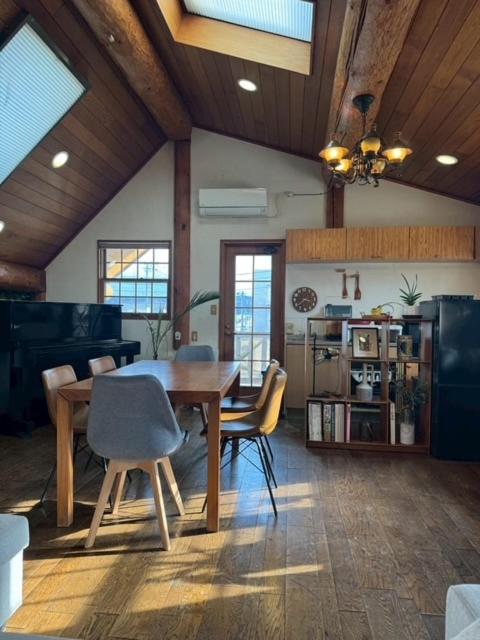 a dining room with a wooden table and chairs at Attico Inn ムーミン公園近く in Hanno