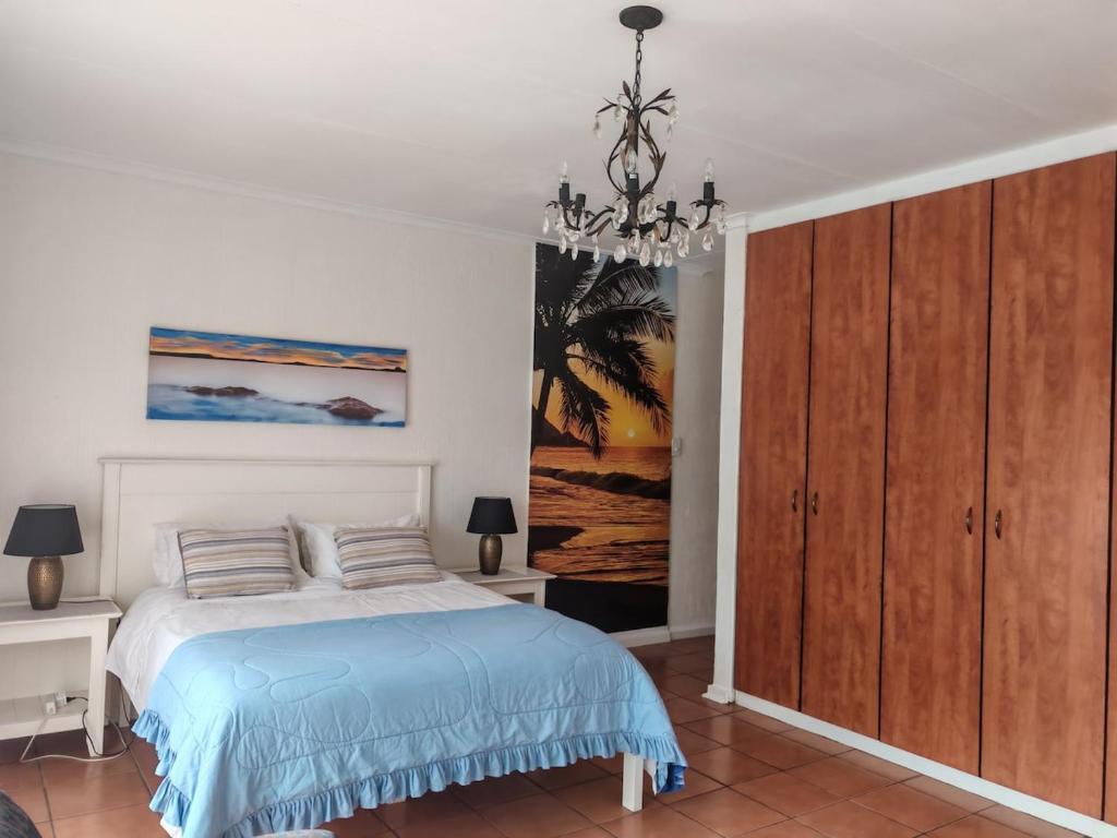 a bedroom with a bed and a chandelier at Sunset on Silver Beautiful self catering Studio apt in Roodepoort