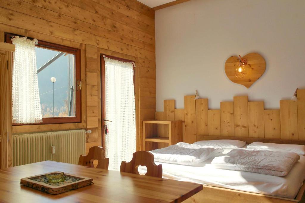 a bedroom with a bed and a table and a window at Valles Vacanze - ski in & ski out in Falcade