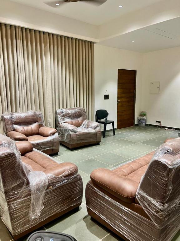 a living room with three leather couches and a chair at Weekend villa in Rajkot