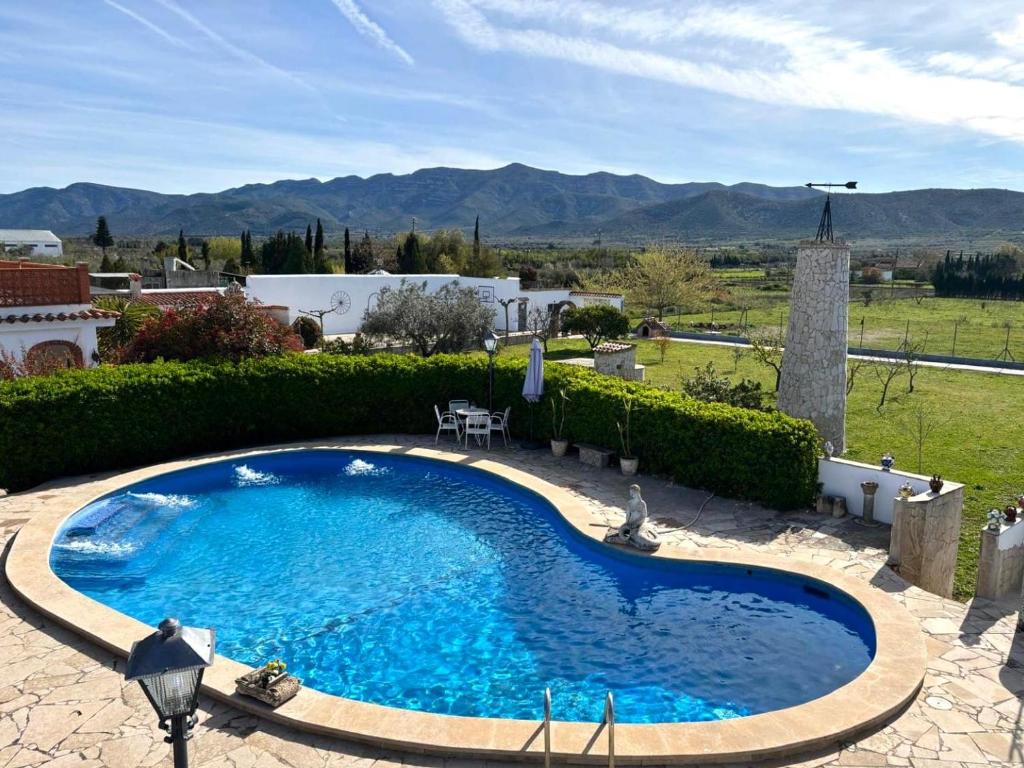 a large blue pool in a yard with mountains in the background at Finca el Placer in Ulldecona