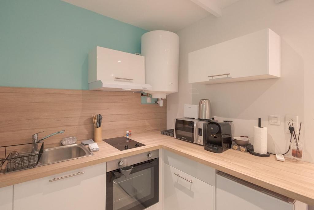 a kitchen with white cabinets and a sink and a microwave at La Perle Bleue - air conditioning - ground floor in Bourg-en-Bresse