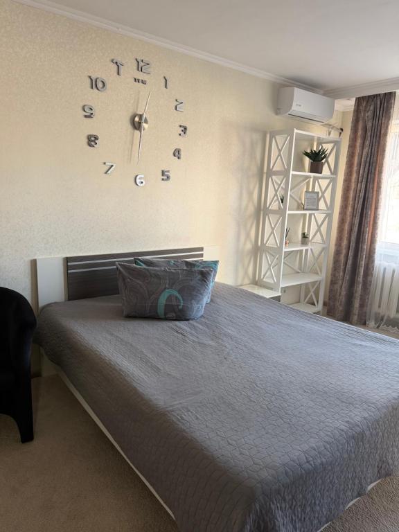 a bedroom with a bed with a clock on the wall at Apartments on Priportovaya,35 in Cherkasy
