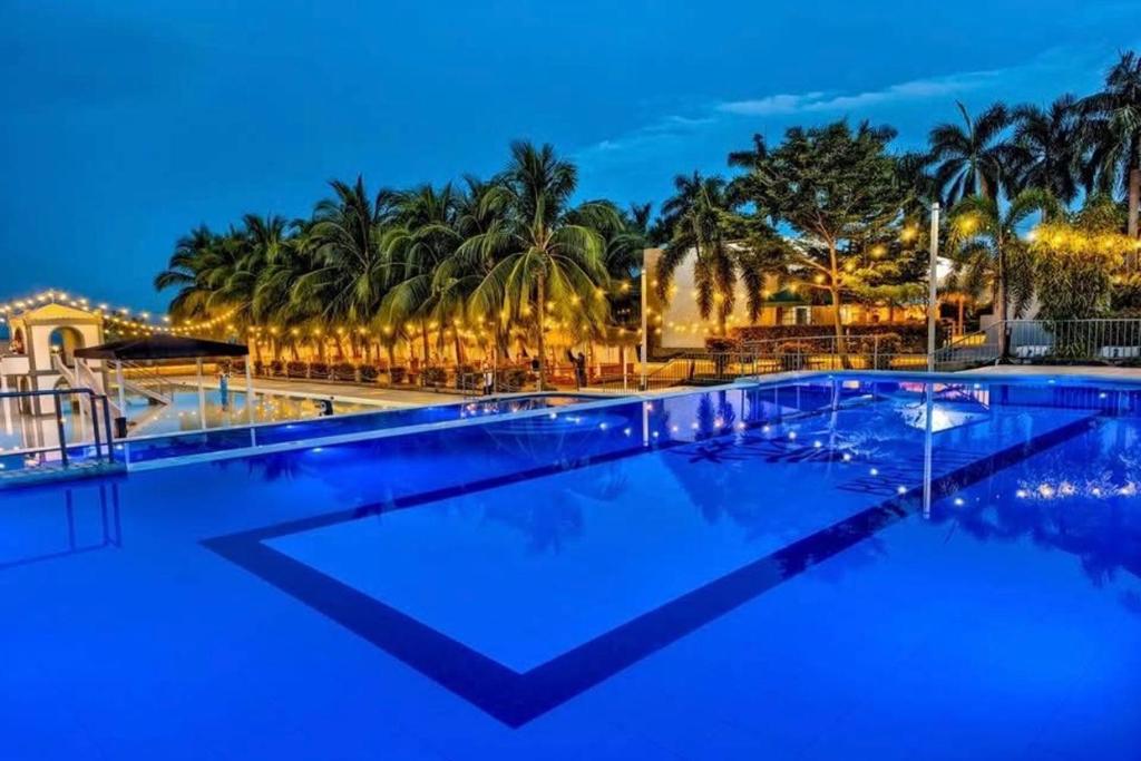 a swimming pool with palm trees in the background at Brevant Pool Club and Resort in El Salvador