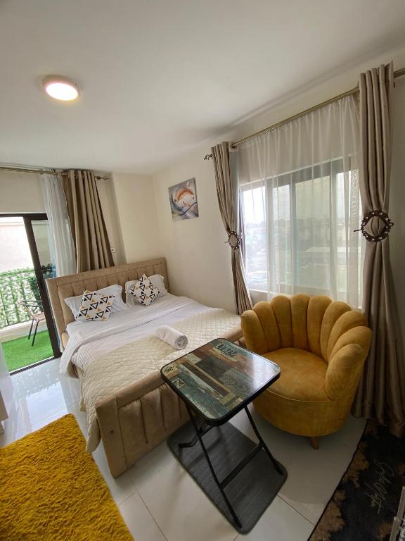 a bedroom with a bed and a chair and a window at Luxore Apartments Syokimau No E803 in Syokimau