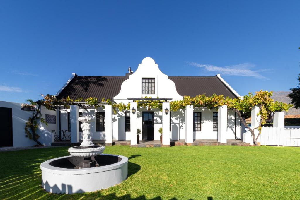 a white house with a fountain in the yard at Shelanti Guesthouse in Ceres