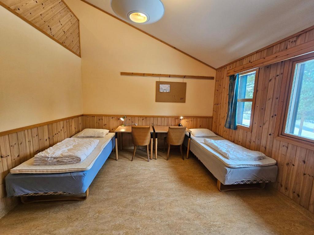 a room with two beds and a table in it at Alta Folkehøgskole in Alta