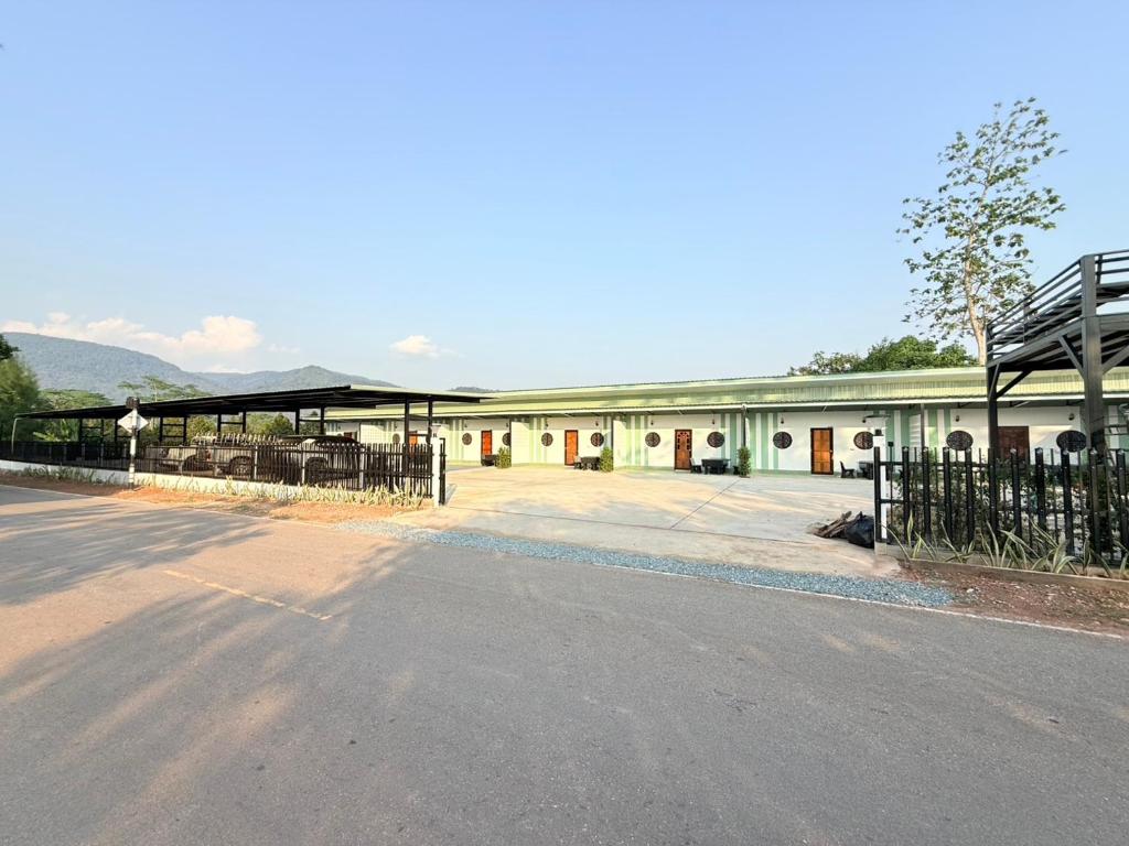 a white building with a fence and a street at Khaochamao View in Ban Nam Pen