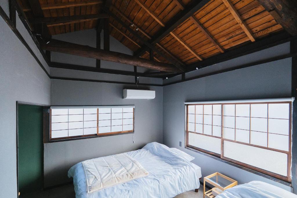a bedroom with two beds and two windows at oribe guesthouse in Tajimi