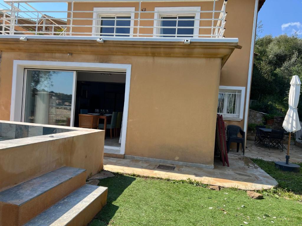 a house with a balcony and a patio at Ou Souleou appartement 3 étoiles dans villa Spa béton jardin vue mer et colline in Bormes-les-Mimosas