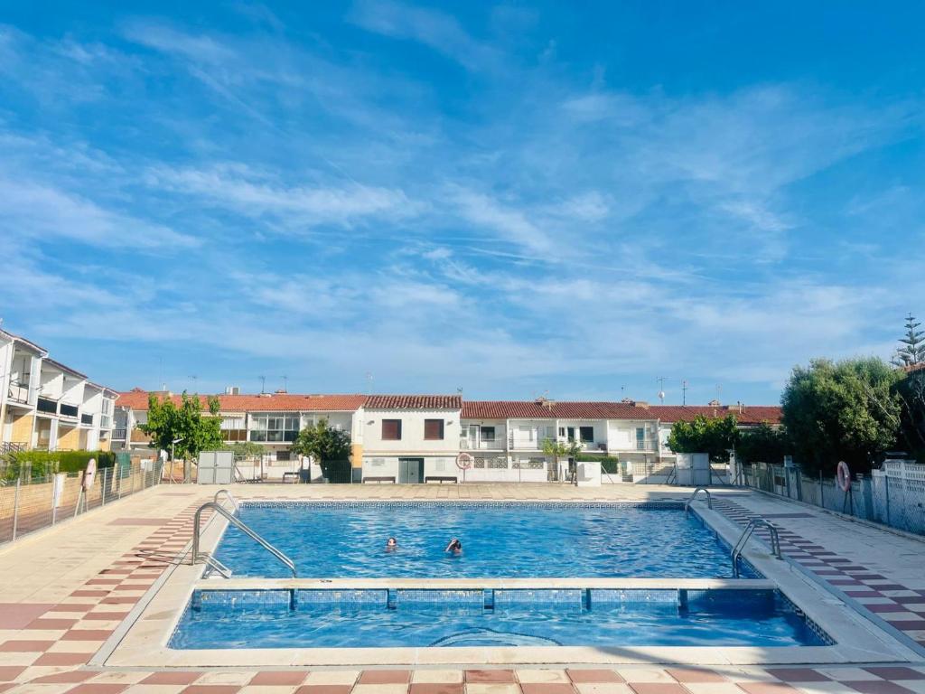 a swimming pool with people in the water at Casa con piscina ideal vacaciones en la playa in Comarruga