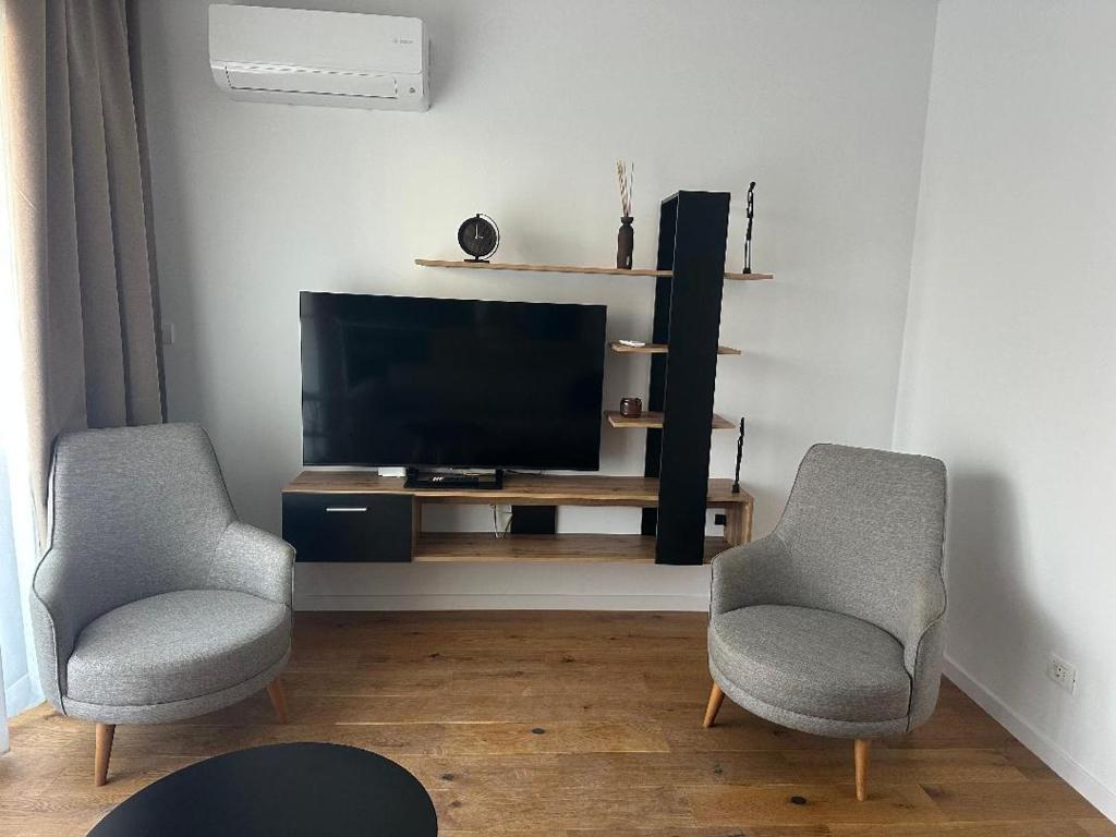 a living room with two chairs and a television at LaRa Apartament in Timişoara