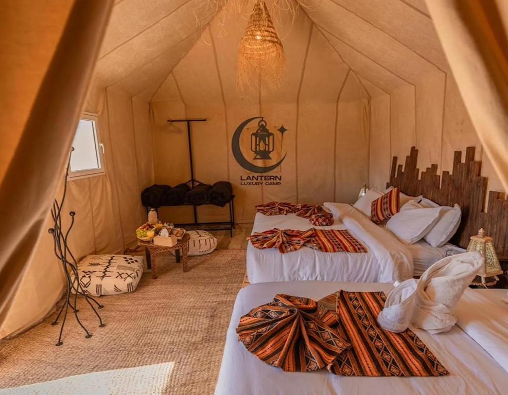 a room with three beds in a tent at Lantern Luxury Camp in Merzouga