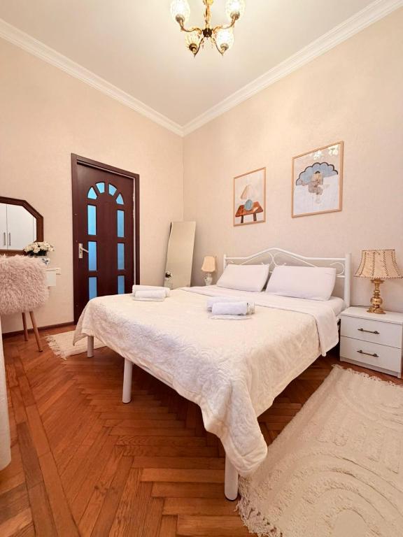 a bedroom with a large white bed and a chandelier at Sunny Flower in Kutaisi