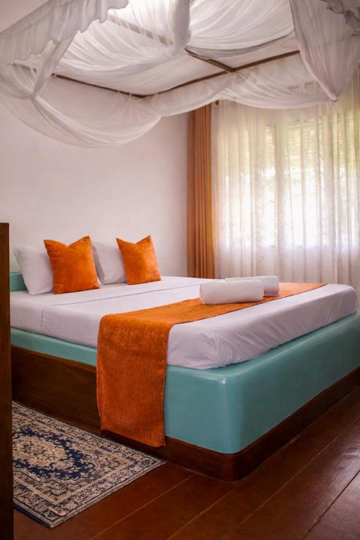a bedroom with two beds with orange and white pillows at Elephant Villa Diani in Ukunda