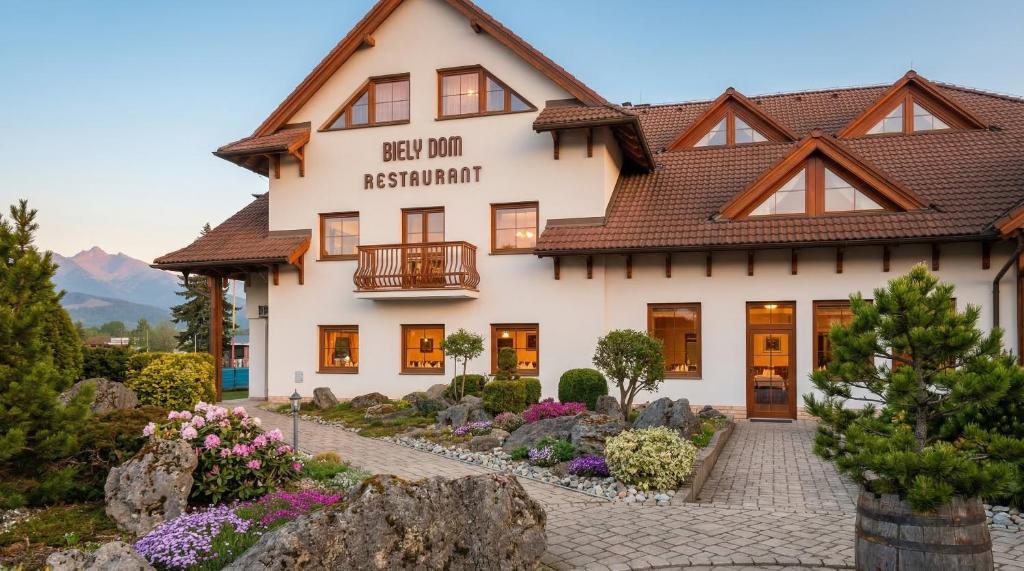 a house in the mountains with flowers in front of it at Biely Dom in Ružomberok