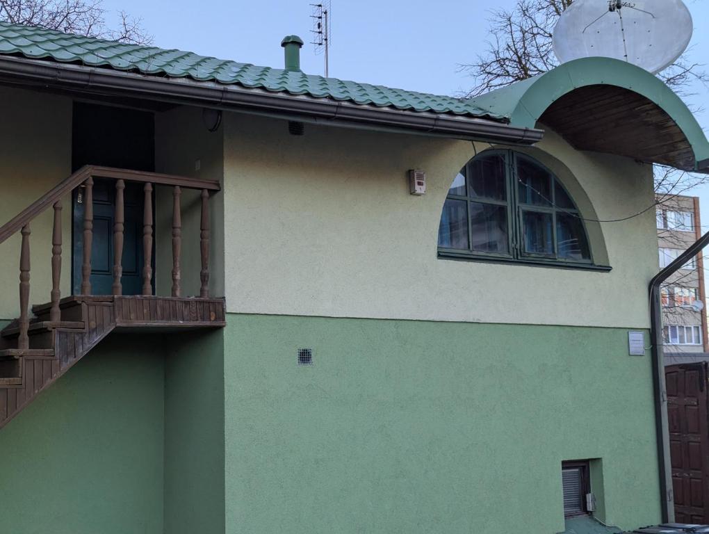 a green house with a balcony and a window at Cousy Center House in Šiauliai