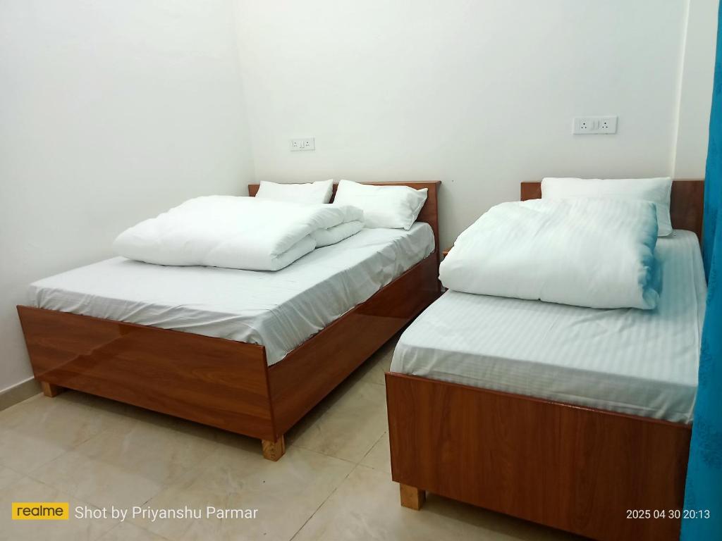 two beds sitting next to each other in a room at Hukkam Homestay in Barkot