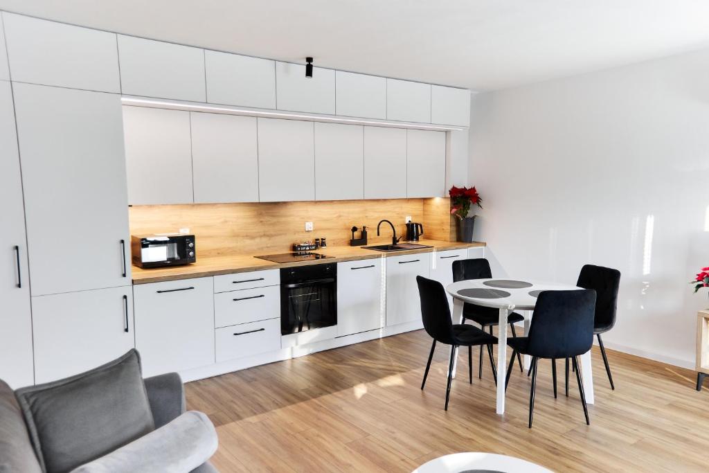 a kitchen with white cabinets and a table and chairs at Park & Town Apartment in Drawsko Pomorskie
