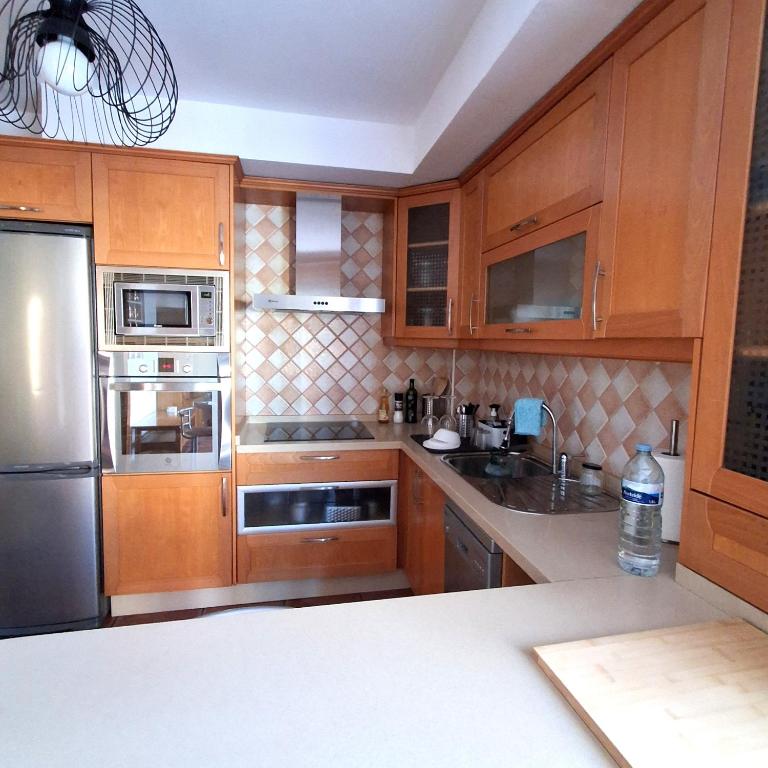 a kitchen with wooden cabinets and stainless steel appliances at Sun Home Arinaga in Arinaga