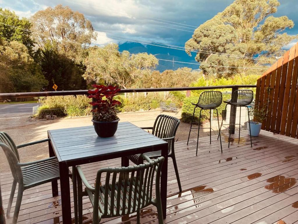 a table and chairs on a wooden deck with a plant at No 43 Guesthouse in Mount Beauty