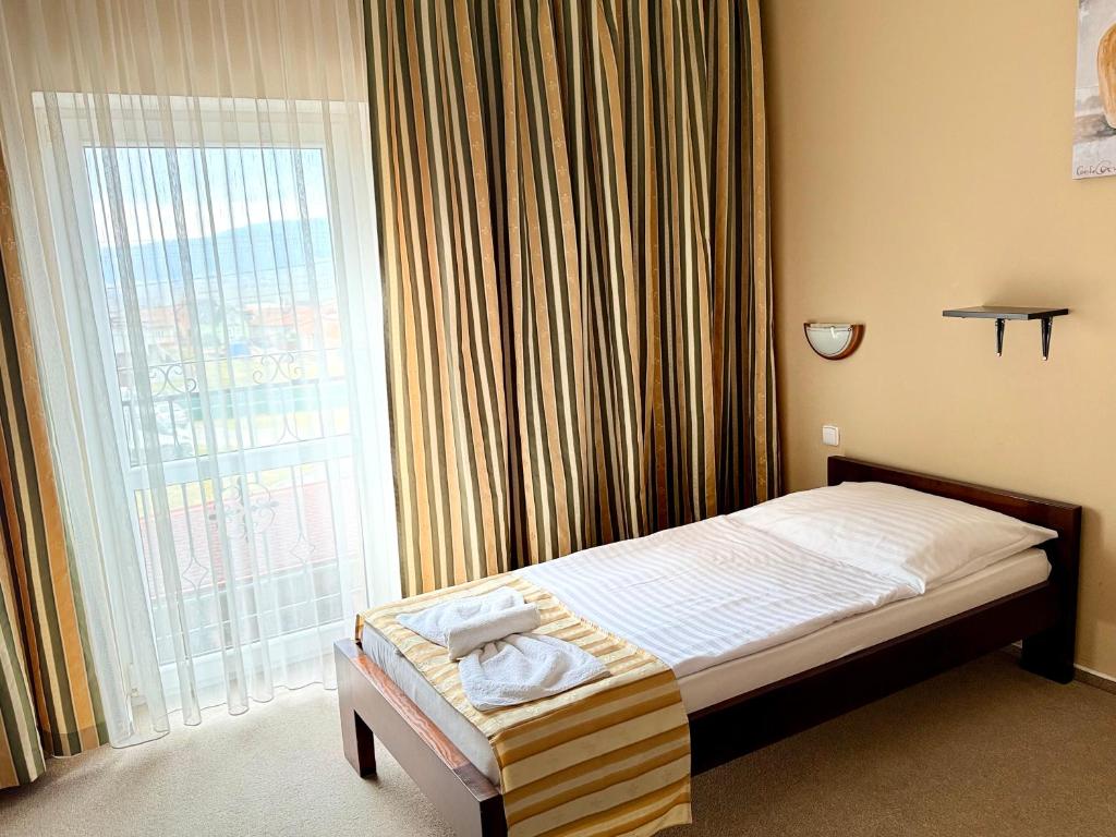 a bedroom with a bed and a large window at Restaurant and Pension Stenly in Spišský Štvrtok