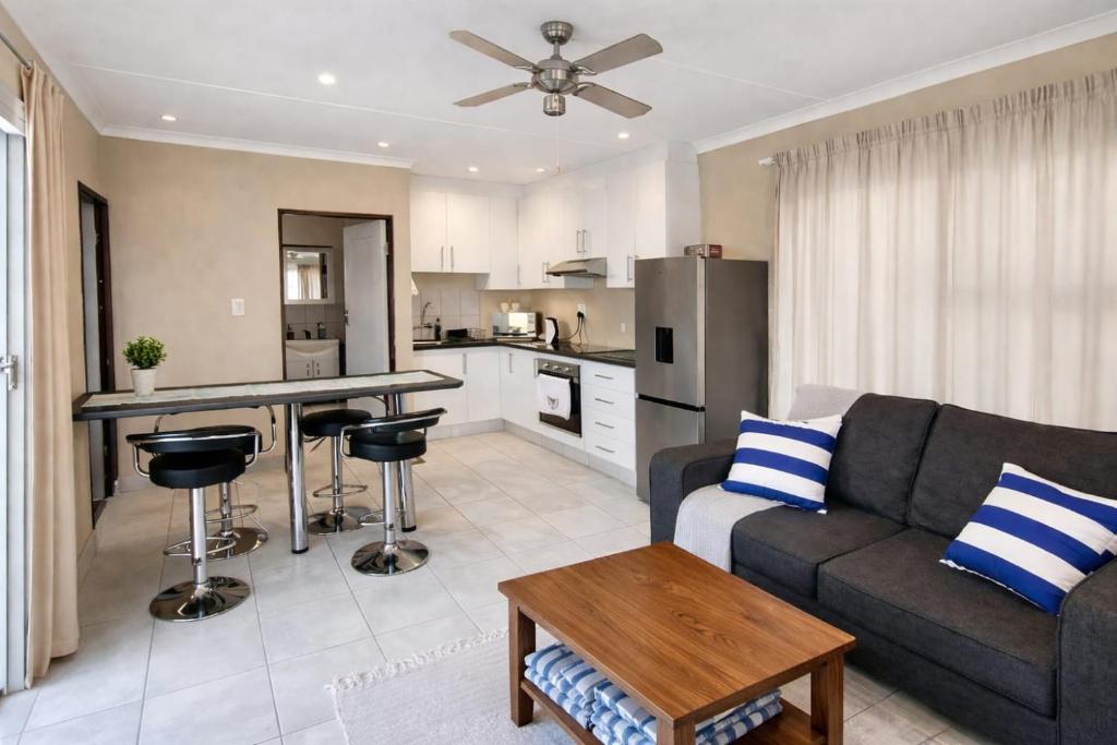 a living room with a couch and a kitchen at Honey Cove in Mossel Bay