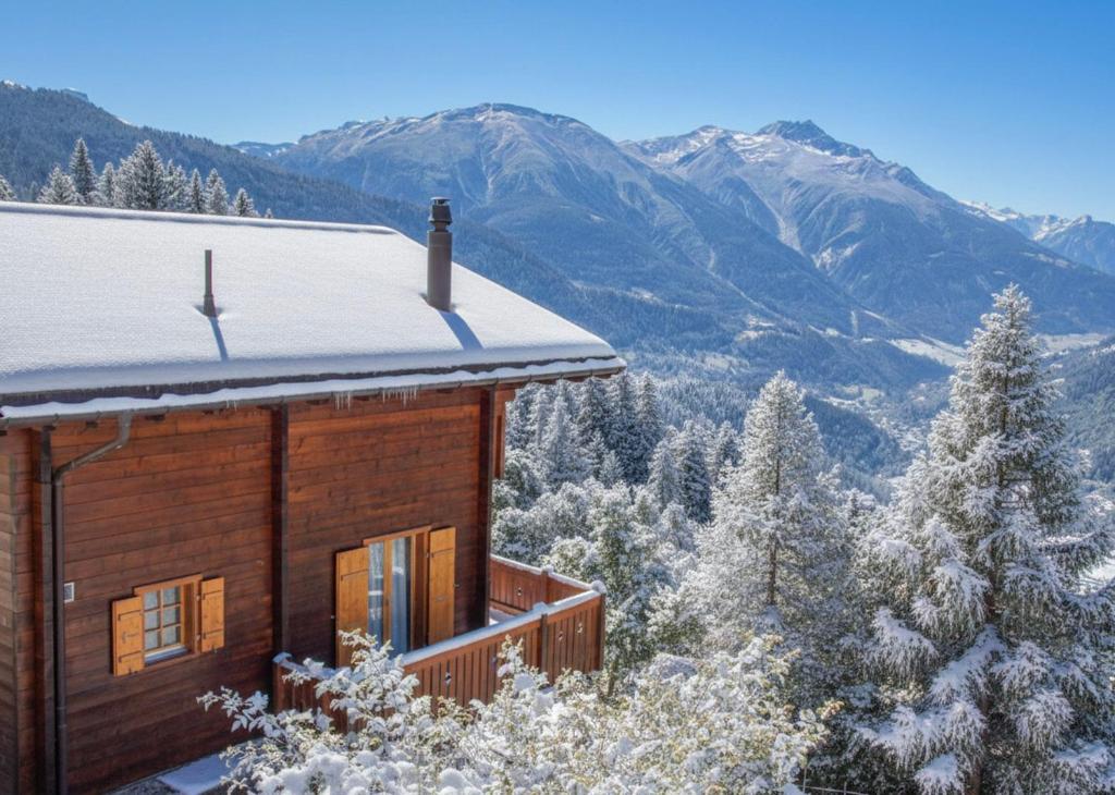 a cabin in the snow with mountains in the background at Chalet Charis in Bellwald
