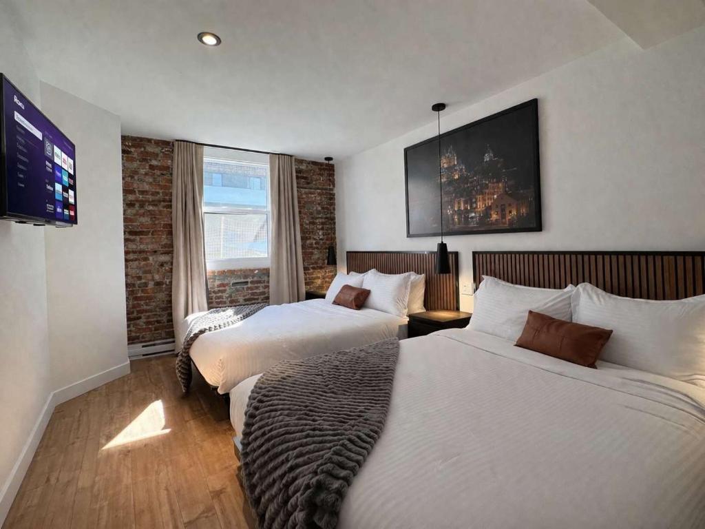 a hotel room with two beds and a flat screen tv at Room with 2 Queen-Size Beds Downtown Quebec in Quebec City