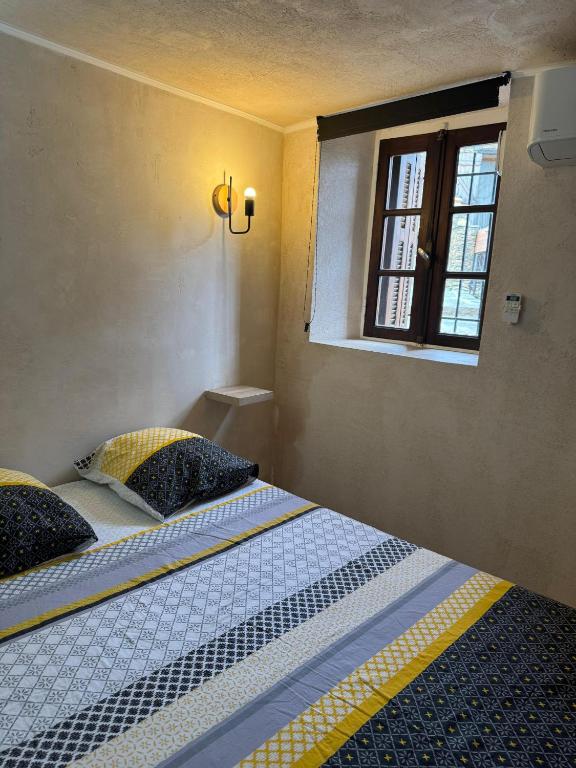 a bedroom with a bed and a window at Appartement cosy dans les ruelles de Pietranera in San-Martino-di-Lota