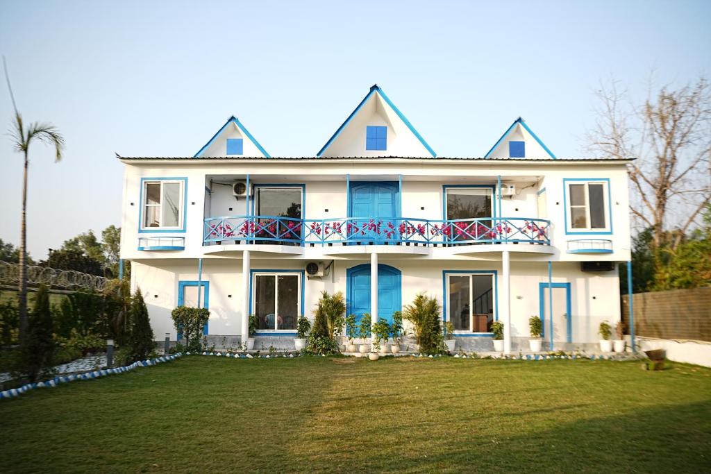 a large white house with blue windows and a yard at Sundown Resort in Noida