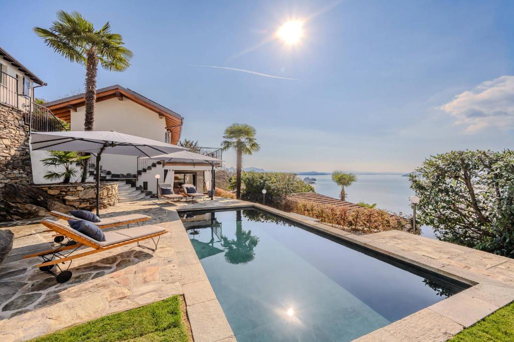 a swimming pool with two chairs and an umbrella at Villa Suna Paradiso in Verbania