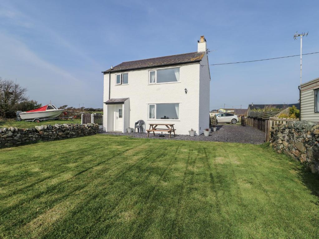a white house with a grassy yard in front of it at Pentre Iago in Holyhead