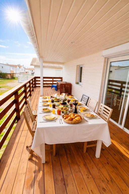 a table with plates of food on a deck at Le Chalet Beach Access 8 Pers in Gruissan